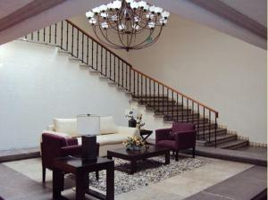 a living room with a couch and two chairs and a staircase at Hotel Gobernador in Durango