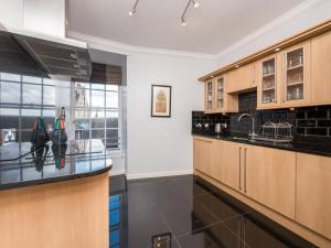 a kitchen with wooden cabinets and black counter tops at Festival Lets in Edinburgh