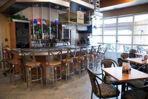 a restaurant with a bar with wooden tables and chairs at Auberge l'Ambassadeur in Amqui