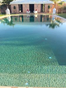 una piscina de agua clara frente a una casa en Villas Fleurs Marrakech, en Marrakech