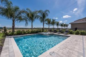 a swimming pool with palm trees in a yard at Bright Home with Water Park Access near Disney by Rentyl - 7576M in Orlando