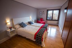 a bedroom with a bed and a red chair at Casa Rural Arraigorri in Hernani