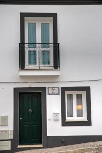 タヴィラにあるCasa do Altoの緑のドアとバルコニー付きの建物