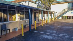 an empty parking lot next to a building with yellow poles at Windsor Motel in Windsor