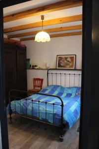 a bedroom with a bed with a blue comforter at maison de la salamandre in Ribes