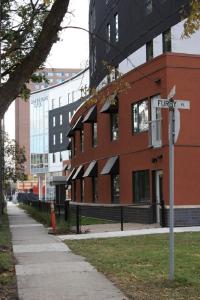 un panneau de rue devant un bâtiment en briques rouges dans l'établissement UWinnipeg Downtown Accommodations, à Winnipeg