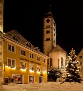 a christmas tree in front of a building with a clock tower at Hotel Alte Post in Wangen im Allgäu