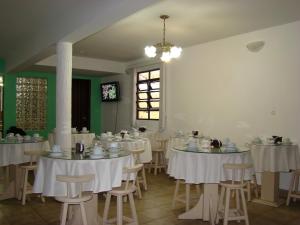 a dining room with white tables and chairs at Pousada Volare in Matinhos