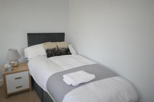 1 dormitorio con 2 camas y mesita de noche con toalla blanca en Whole House - Sleeps 5 - near town centre - off road parking en Hinckley