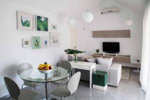 un soggiorno bianco con tavolo e sedie in vetro di Maspalomas Suites a Maspalomas