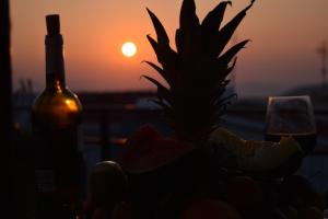 a bottle of wine and a pineapple in front of the sunset at Konstantinos in Áno Valsamóneron