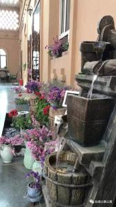 a water fountain in a building with flowers at Turpan Silk Road Lodges - The Vines in Turfan