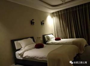 a hotel room with two beds and a window at Turpan Silk Road Lodges - The Vines in Turfan