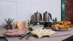 une table recouverte de différents types de pain et de viande dans l'établissement La Villa Hotel, à Cordeirópolis