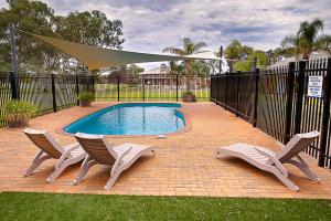 a swimming pool with two chairs and a umbrella at Standpipe Golf Motor Inn in Port Augusta