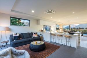 a living room with a couch and a kitchen at Lakefront Luxury by Amazing Accom in Queenstown