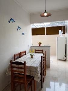 d'une salle à manger avec une table, des chaises et un réfrigérateur. dans l'établissement Condomínio Ville II, à Ubatuba