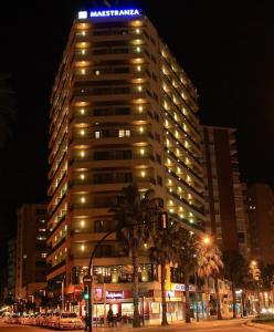 a tall building with a blue sign on top at night at Hotel MS Maestranza Málaga in Málaga