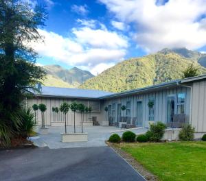 un grand bâtiment avec des montagnes en arrière-plan dans l'établissement Franz Josef Oasis, à Franz Josef