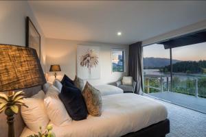 a bedroom with a bed and a large window at Lakefront Luxury by Amazing Accom in Queenstown +13 photos