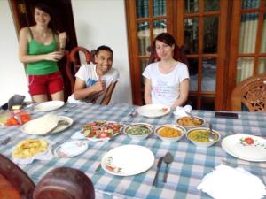 un gruppo di persone seduti intorno a un tavolo con cibo di Thuruliya Residence a Sigiriya