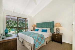 a bedroom with a large bed and a window at Kananda in Noosa Heads