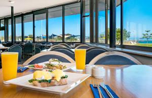 a table with two plates of food and orange juice at Ocean Centre Hotel in Geraldton