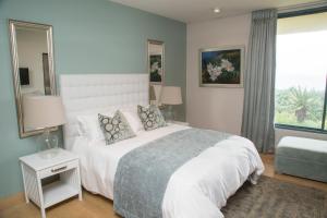 um quarto com uma grande cama branca e uma janela em Misty Blue Bed and Breakfast em Durban