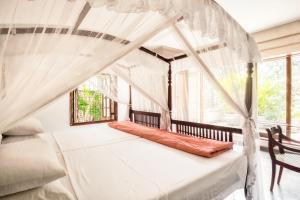 ein Schlafzimmer mit einem Himmelbett und einem Fenster in der Unterkunft Mount Lodge Boutique Hotel in Mount Lavinia