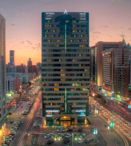 um edifício alto numa cidade à noite com trânsito em Al Maha Arjaan by Rotana em Abu Dhabi