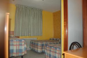 a room with two beds and a window at Hostal Mays in Numancia de la Sagra