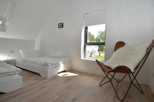 ガガーにあるThe Strandwood House in Gagerの椅子とベッド、窓が備わる客室です。