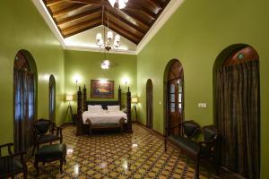 a bedroom with a bed in a room with green walls at Surya Kiran Heritage Hotel in Panaji