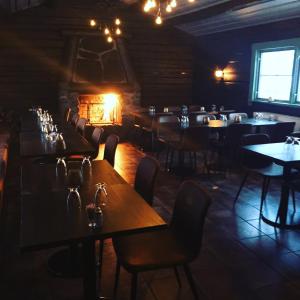 a dining room with tables and chairs and a fireplace at Hotel Akerlund in Jokkmokk