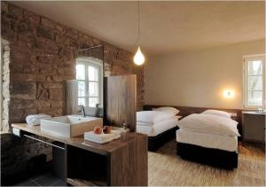 1 dormitorio con 2 camas, lavamanos y pared de piedra en Landgrafen-Mühle en Wallhalben