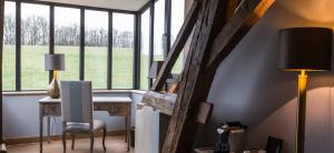 a room with a desk and a lamp and windows at Domaine de Rymska & Spa - Relais & Châteaux in Saint-Jean-de-Trézy