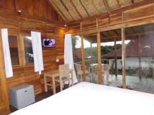 Habitación con paredes de madera y ventanas con mesa y sillas. en Green Bowl Beach Villas, en Uluwatu