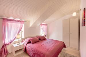 a bedroom with a pink bed and a window at Holiday Home Nada in Dubrovnik