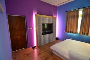 a bedroom with purple walls and a bed and a television at Home Coming in Xiaoliuqiu