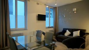 a living room with a glass table and a clock on the wall at Little Suite - Prisca in Lille