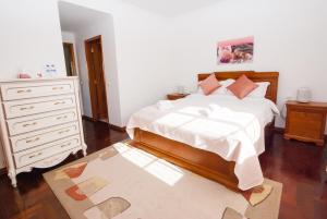 a bedroom with a white bed with a dresser and a drawer at Grace Villa in Aldeia de Juso
