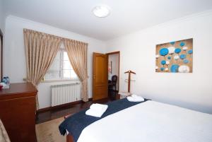 a bedroom with a large white bed and a window at Grace Villa in Aldeia de Juso