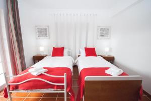two beds in a room with red and white sheets at Grace Villa in Aldeia de Juso