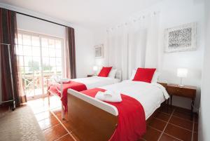 two beds in a white room with red sheets at Grace Villa in Aldeia de Juso
