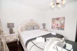 a white bedroom with a bed and a chair at Grace Villa in Aldeia de Juso