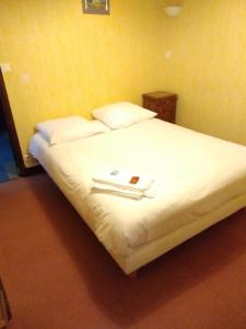 um quarto com uma cama com lençóis brancos e almofadas em Le Saintongeais em Berneuil