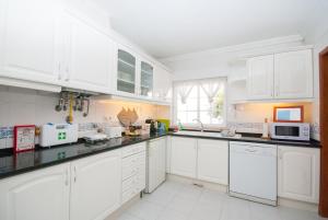 a white kitchen with white cabinets and appliances at Grace Villa in Aldeia de Juso