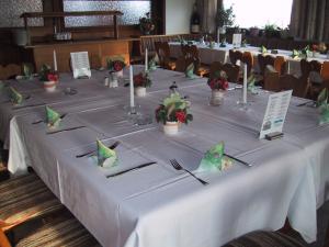 a long table with a white table cloth and flowers at Berggasthof Hinhart in Regen