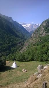 una tienda blanca en un campo con montañas al fondo en Tipis nature, en Gavarnie