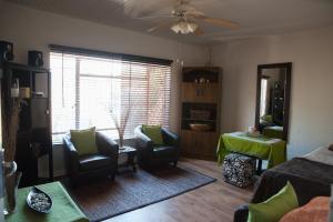 a living room with two chairs and a ceiling fan at The Lazy Grape Guest Lodge & Spa in Benoni